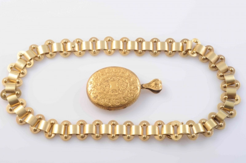 AN EARLY VICTORIAN LOCKET PENDANT, the heavy oval articulated link chain suspending a detachable oval locket pendant set with engraved scrolling and floral details to the entirety, suspending from an articulated tapering oval bale with similar engraved de