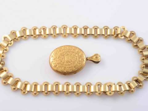 AN EARLY VICTORIAN LOCKET PENDANT, the heavy oval articulated link chain suspending a detachable oval locket pendant set with engraved scrolling and floral details to the entirety, suspending from an articulated tapering oval bale with similar engraved de thumbnail