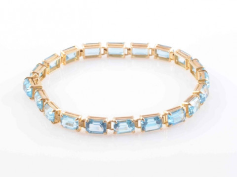 A BLUE TOPAZ BRACELET, the twenty rectangular cut blue topaz each four...