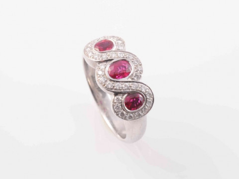 A BURMESE RUBY AND DIAMOND RING, the three oval cut graduating rubies...