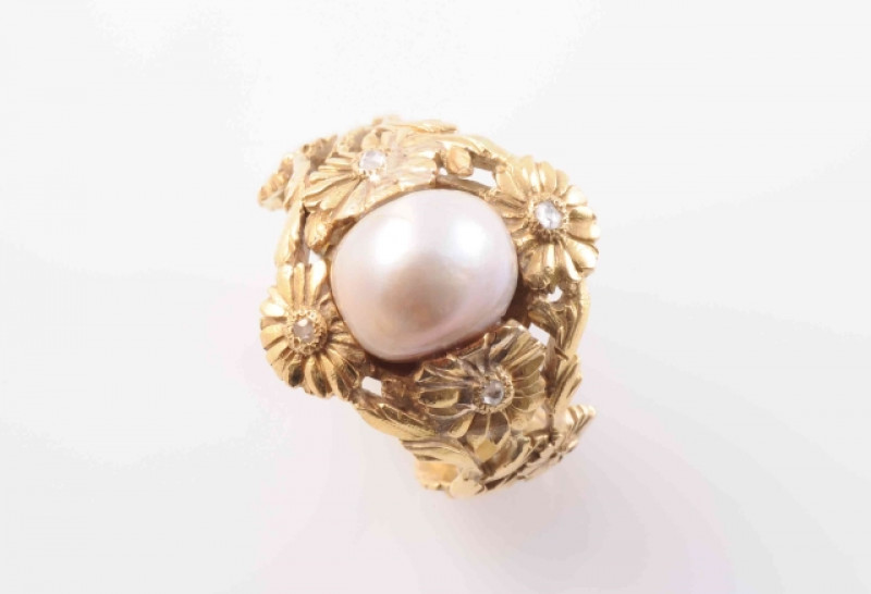 A NATURAL SALTWATER PEARL RING, the large single saltwater pearl set within an elaborately moulded floral mount on a tapering band moulded to the entirety with similar floral details, each flowerhead set to the centre with a single old cut diamond highlig