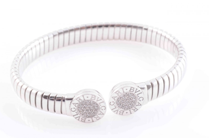 A DIAMOND SET BANGLE BY BULGARI, the circular end terminals set to the centre with nineteen pave set brilliant cut diamonds, within engraved 'BVLGARI' surround, on flexible bracelet. Signed BVLGARI. Diameter 6.5cm. Weight 27.3gms.