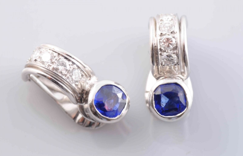 A PAIR OF SAPPHIRE AND DIAMOND EARRINGS, the single round cut collet set sapphire to the top of a simple curved mount set with four brilliant cut diamond highlights, on clip back fittings. Stamped KT18. Total weight 4.9gms.