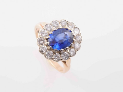 A SAPPHIRE AND DIAMOND RING, the oval cut sapphire fourteen claw set within...