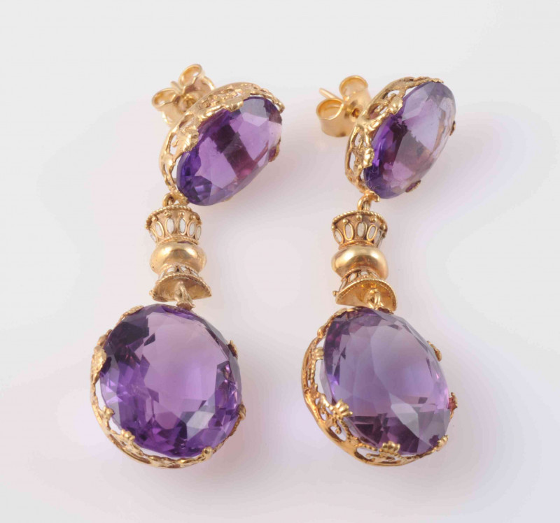 A PAIR OF AMETHYST EARRINGS, circa 1880-1890, the large round cut amethyst set in an articulated pierced detail mount, to the bottom of a rectangular moulded detail mount with subtle white enamel details, in turn to the bottom of a further oval cut amethy