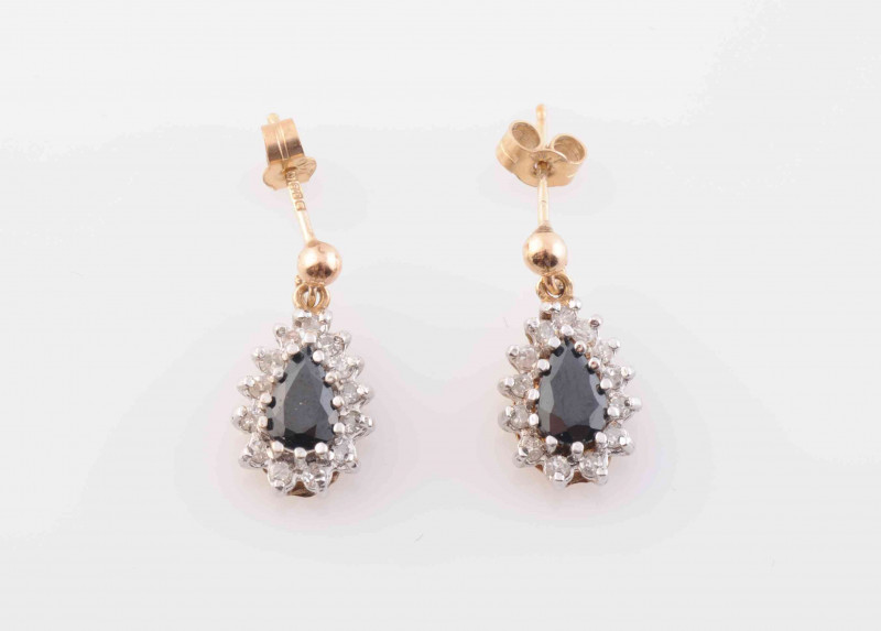 A PAIR OF SAPPHIRE AND DIAMOND EARRINGS, the pear cut sapphire claw set within a surround of thirteen brilliant cut claw set diamonds, set in an open work mount suspending on an articulated link from post and scroll fittings. Stamped 375. Length 1.5cm. To