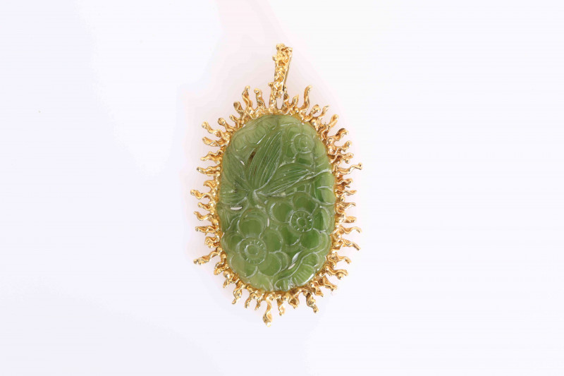 A CHINESE CARVED JADE PENDANT, the oval jade plaque carved with flowerheads and leaves, the mount with irregular edge, the bale stamped 750. 5.5cm by 4cm