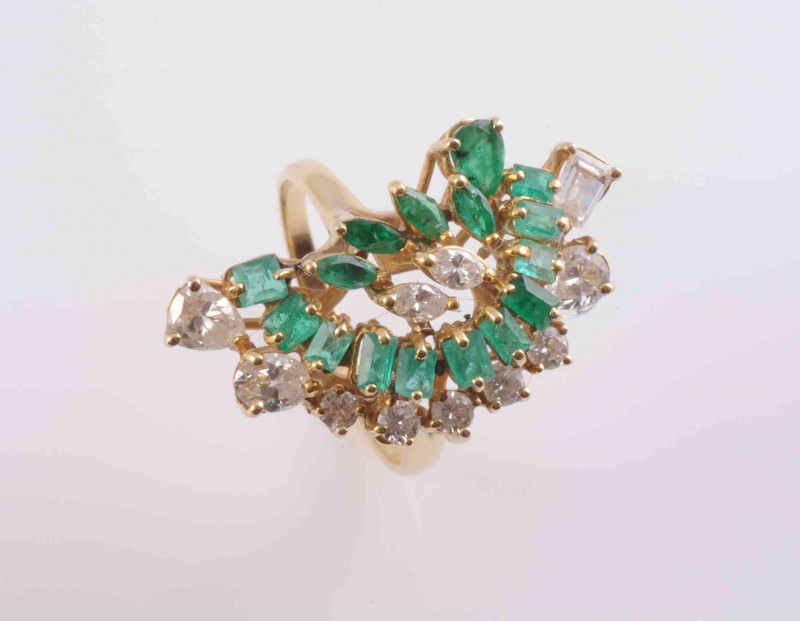 A 1980'S EMERALD AND DIAMOND RING, the abstract open raised mount set throughout with graduating brilliant and pear cut diamonds and graduating rectangular and marquise cut emeralds, on a tapering band. Stamped 18K. Ring size Q, Weight 7.8gms.