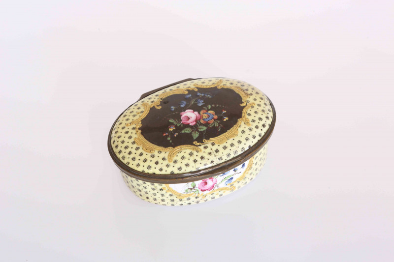 A SOUTH STAFFORDSHIRE ENAMEL SNUFF BOX, CIRCA 1775, oval, the hinged cover centred by a floral spray in polychrome enamels within a frame of tooled gilt C-scrolls, the yellow ground with floral bosses, the sides similarly decorated. 7.5cm by 6cm