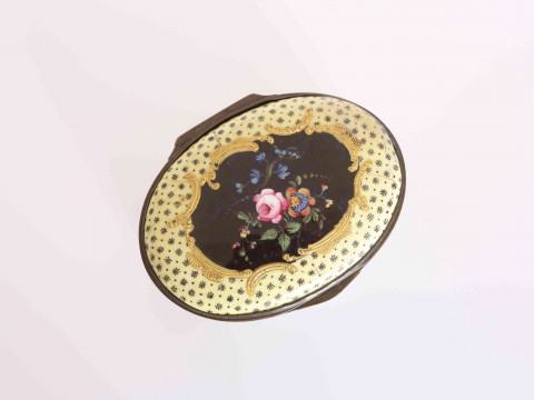 A SOUTH STAFFORDSHIRE ENAMEL SNUFF BOX, CIRCA 1775, oval, the hinged cover centred by a floral spray in polychrome enamels within a frame of tooled gilt C-scrolls, the yellow ground with floral bosses, the sides similarly decorated. 7.5cm by 6cm thumbnail
