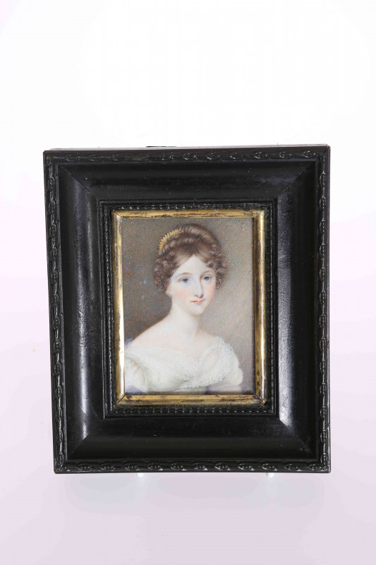 A PORTRAIT MINIATURE OF A YOUNG LADY, EARLY/MID 19TH CENTURY, on ivory, wearing lace decorated dress and hair adornment, in a wooden frame. Overall 14cm by 12cm