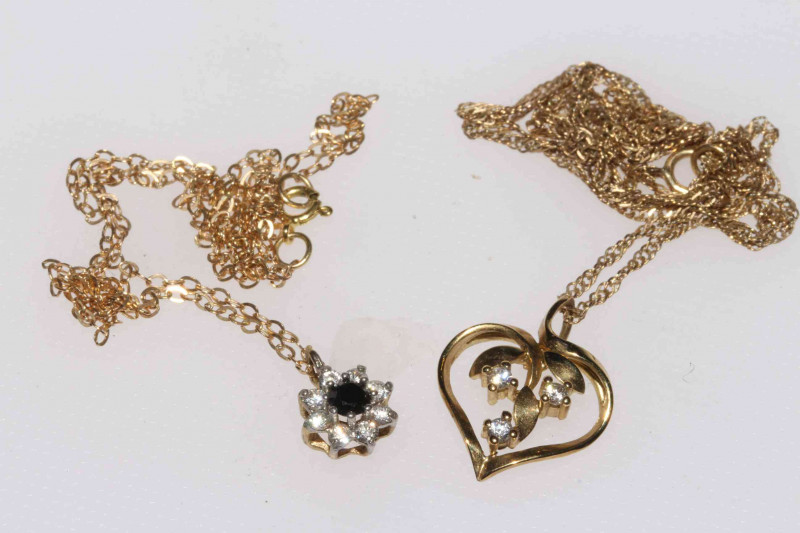 Two 9 carat gold gem set pendants with fine chains, one set with three diamonds, the other sapphire and diamond cluster.