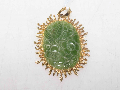 A Chinese carved jade pendant, the oval jade plaque carved with flowerheads...