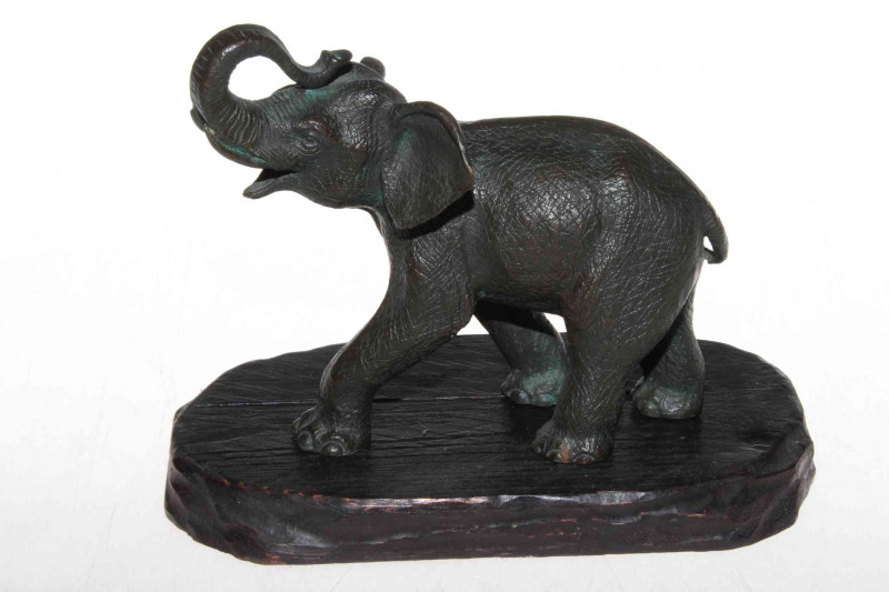 A Japanese Meiji period well detailed bronze elephant with raised trunk, on wooden stand, 15cm.