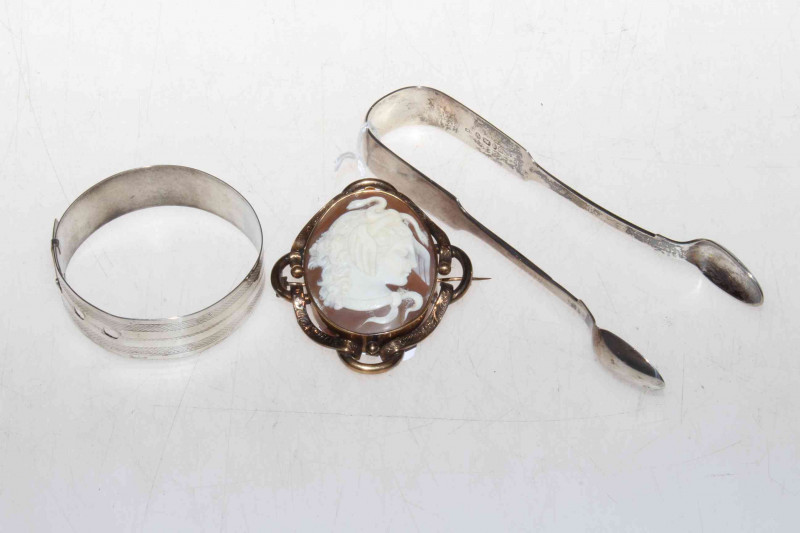 Silver bangle, tongs and cameo brooch.