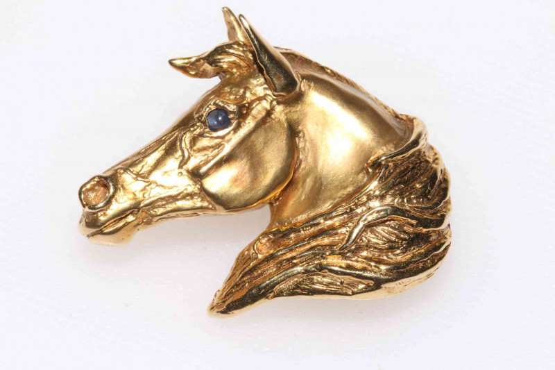 9ct gold horses head brooch, modelled in motion with mane blowing in wind and having cabouchon sapphire eye